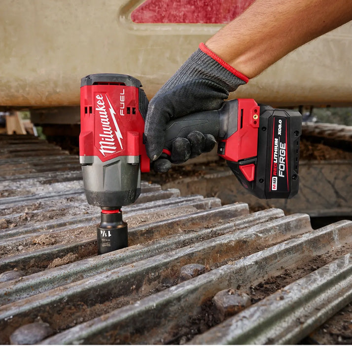 M18 Fuel 1/2" High Torque Impact Wrench in red and black, held by gloved hand, used on metal surface tool.