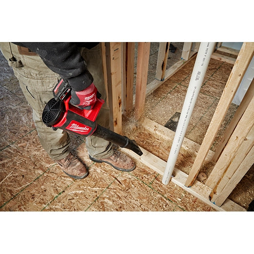Milwaukee M12 Compact Blower 0852-20 red cordless tool clearing sawdust on construction floor.