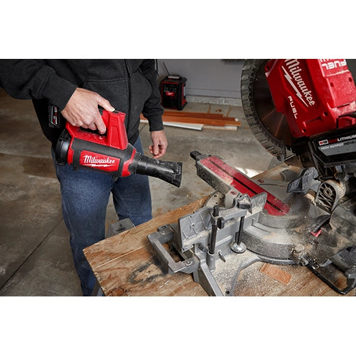 Milwaukee M12 Compact Blower 0852-20 red cordless tool blowing sawdust near power saw tools.