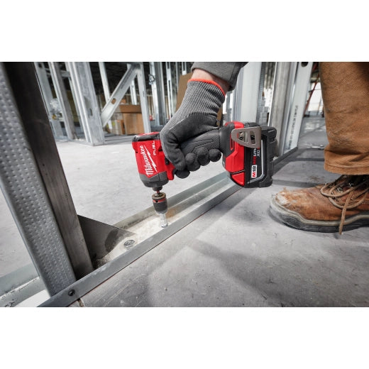 Milwaukee M18 Brushed 1/4 Impact Driver 2953-20 red cordless tool being used on metal framing with gloved hand and.