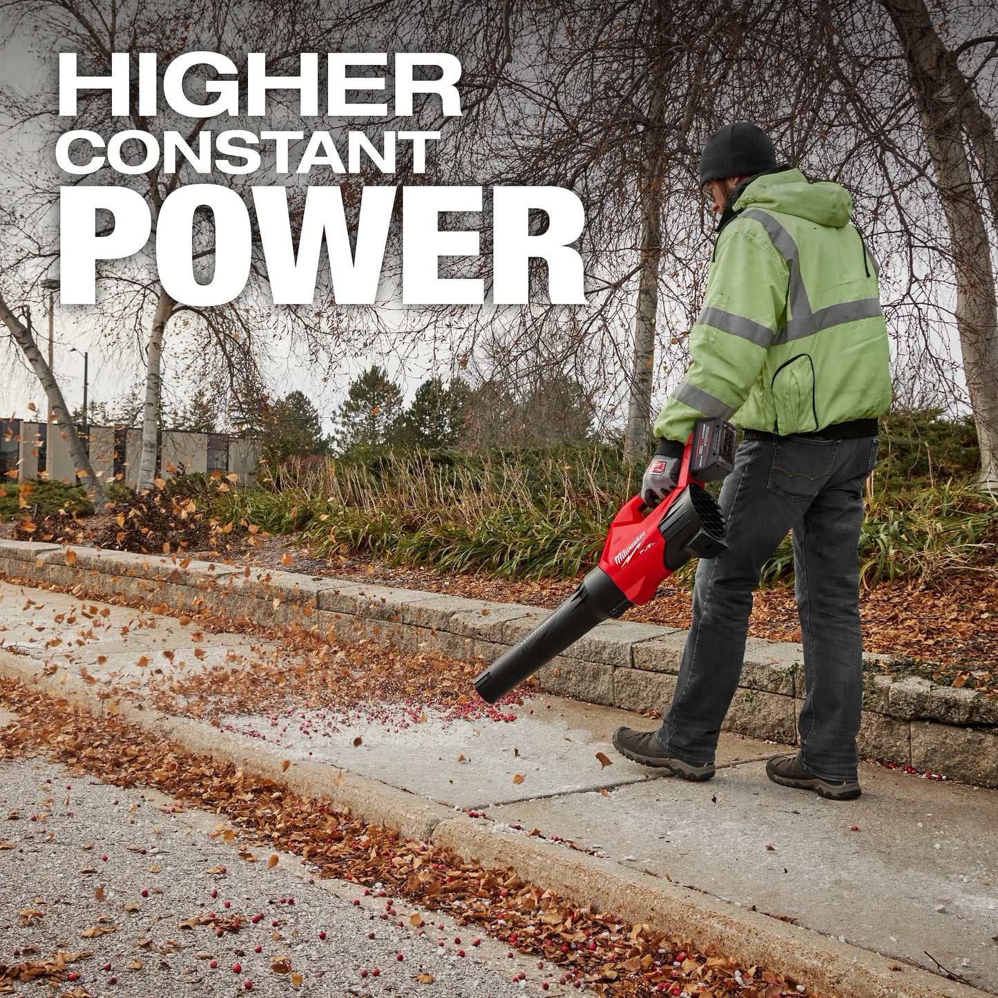 Milwaukee M18 Fuel Blower 3017-20 handheld red and black tool clearing leaves from a sidewalk with a person wearing .