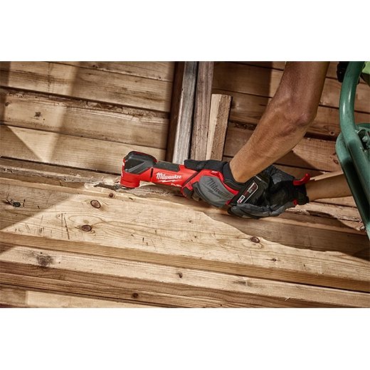Milwaukee M18 Fuel Multi Tool 2836-20 in red and black, cutting wooden planks with a gloved hand, power tool for.