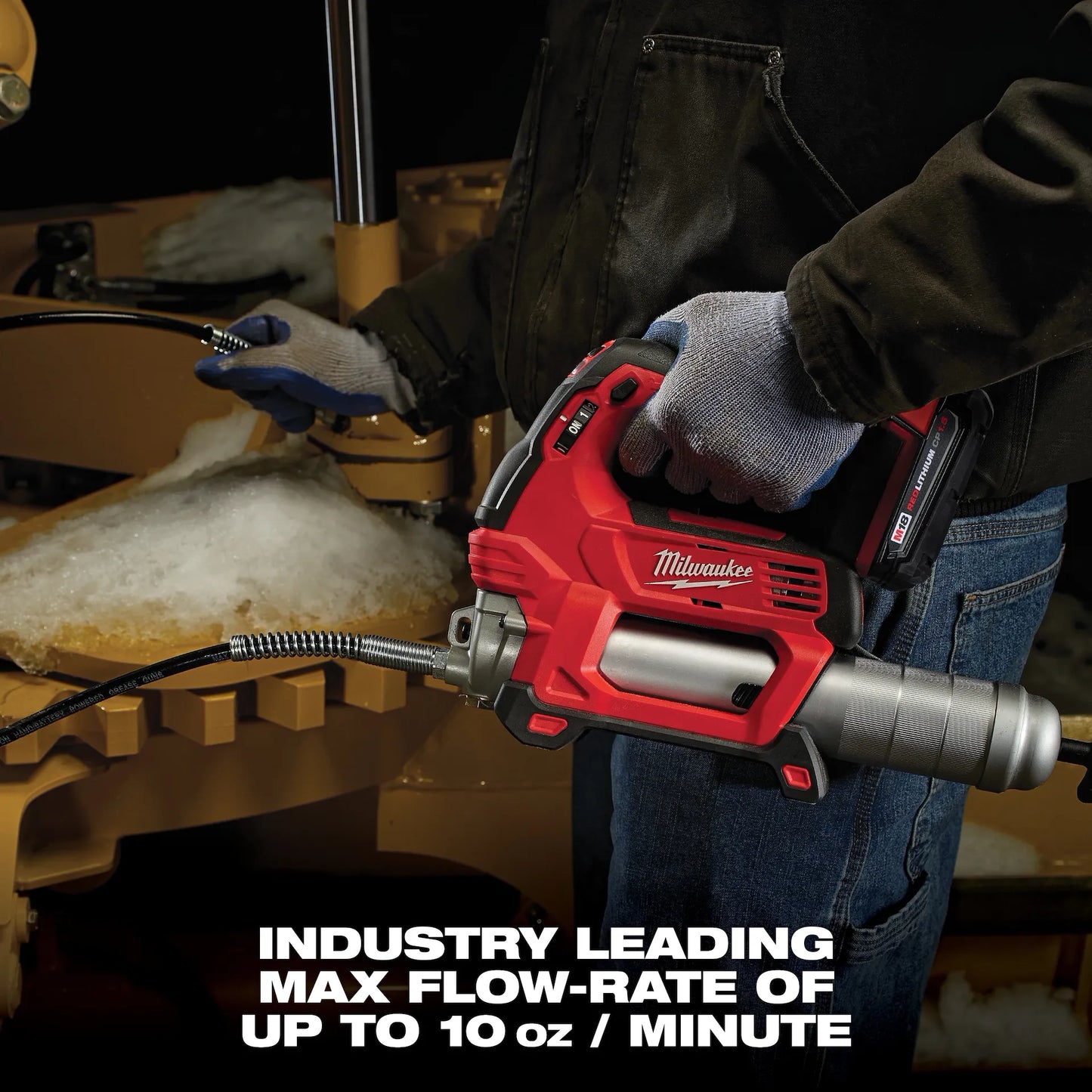 Milwaukee M18 Grease Gun 2646-20 tool held by a worker applying grease to heavy machinery with gloves on.