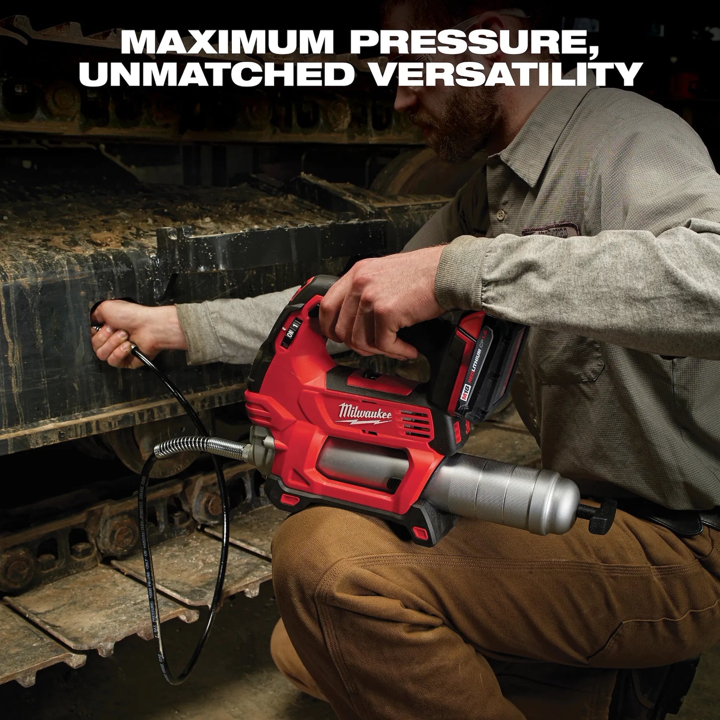 Milwaukee M18 Grease Gun 2646-20 red cordless tool being used on heavy machinery.