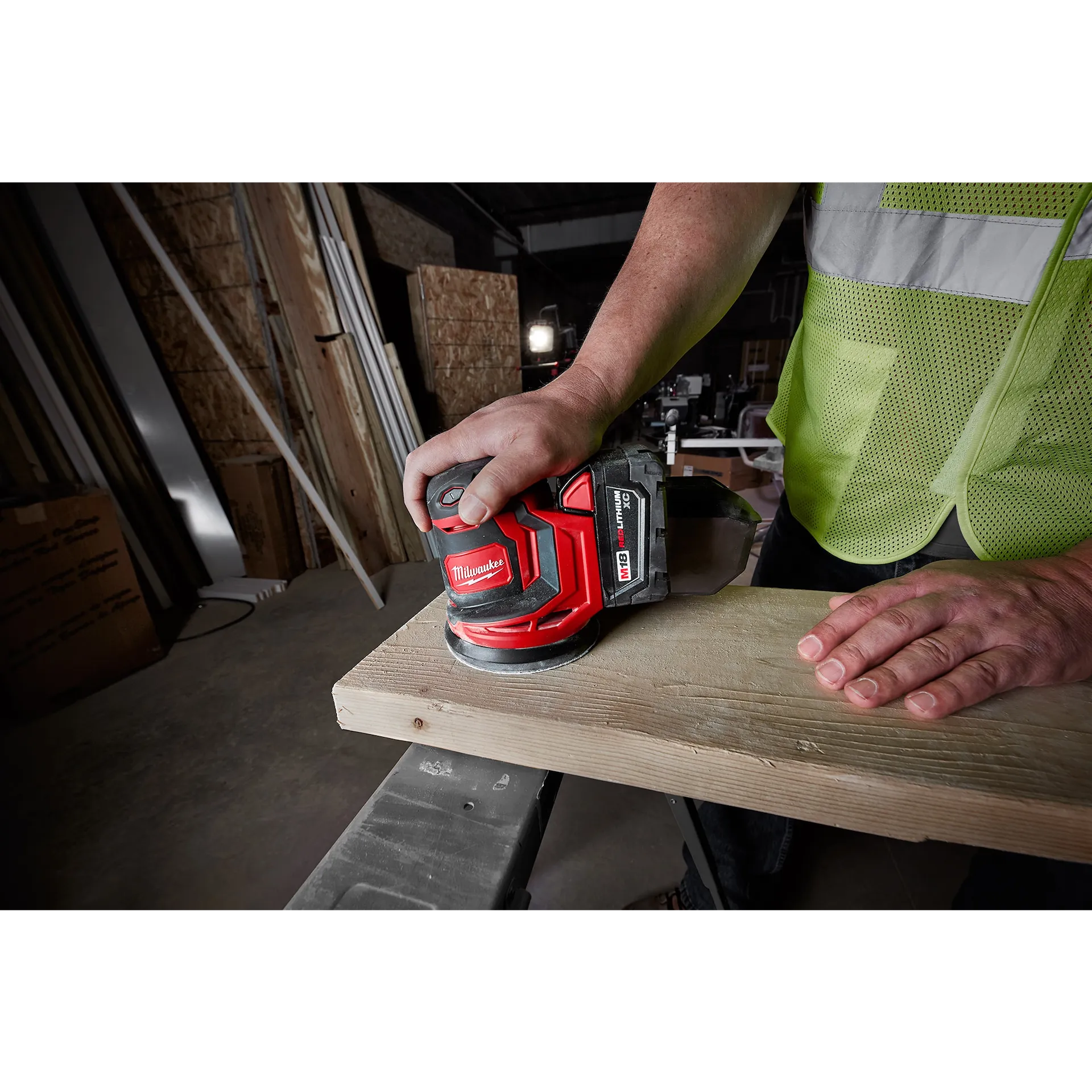 Milwaukee M18 Orbital Sander 2648-20 tool sanding wood with red and black design and ergonomic grip.