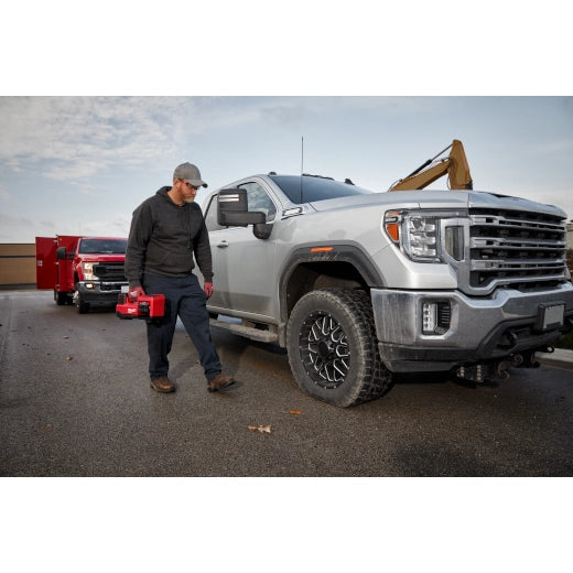 Milwaukee M18 Inflator 2848-20 tool held by worker next to gray pickup truck and red tools truck.